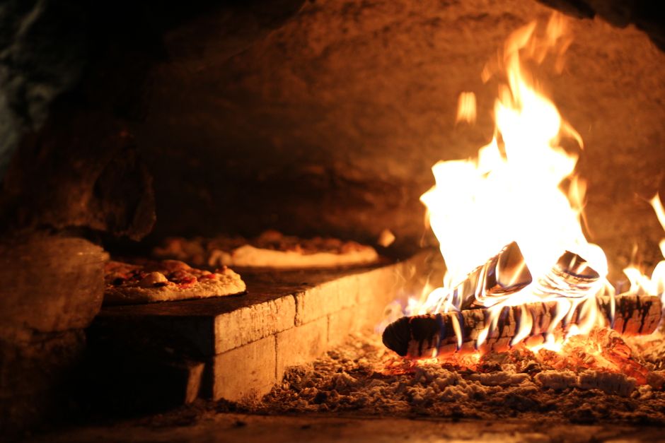 Houtgestookte oven met warme vlammen buiten.